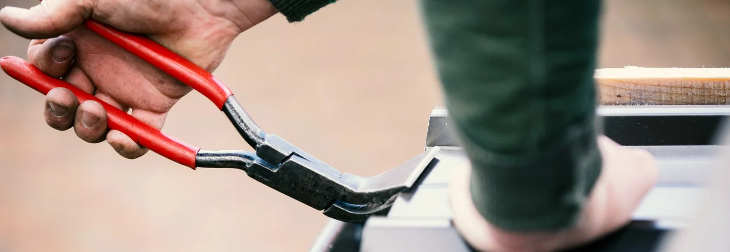 Hand biegt Blech mit Zange